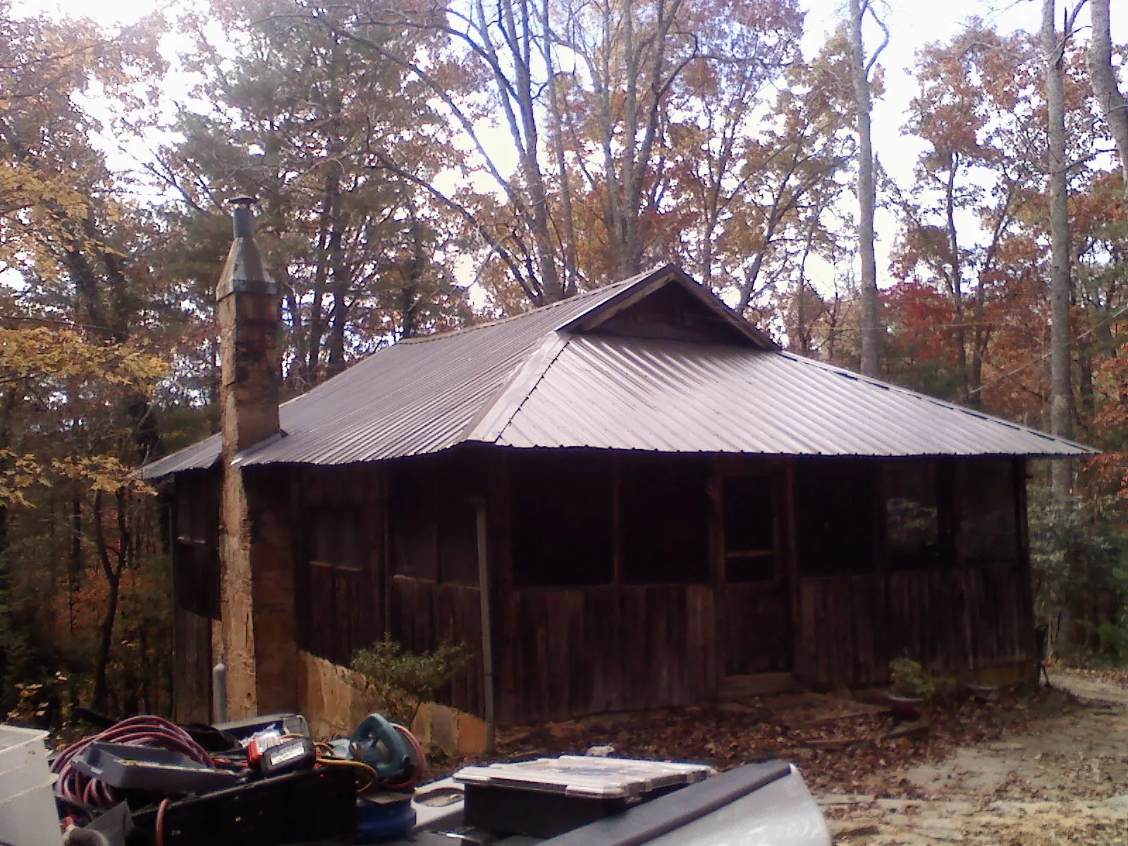Brown metal hip roof on an old cabin with a stone chimney in Belton