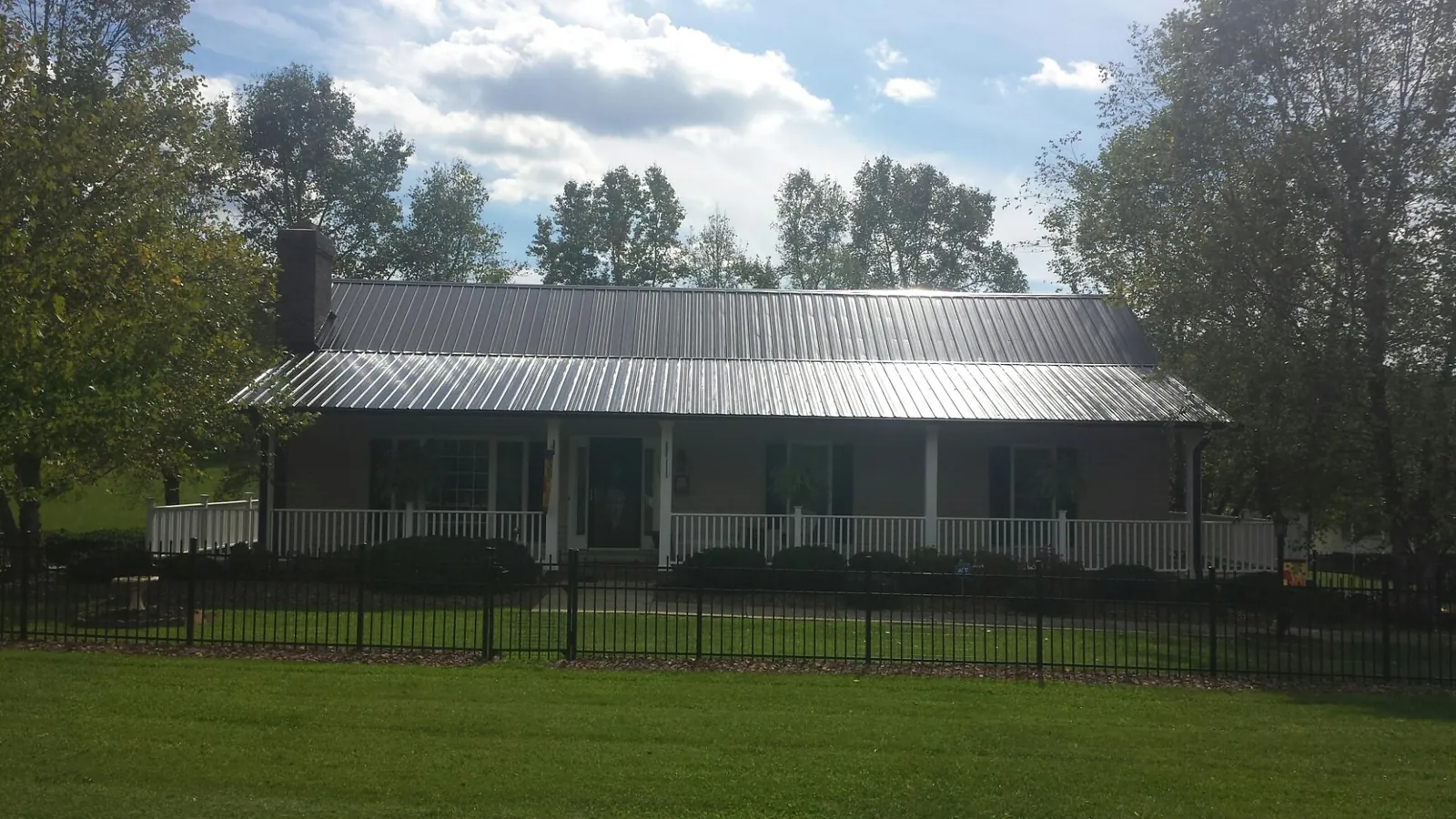 Gray metal roof on a brick ranch with a full width front porch — Gutter Guard Installation work by our crew in Belton